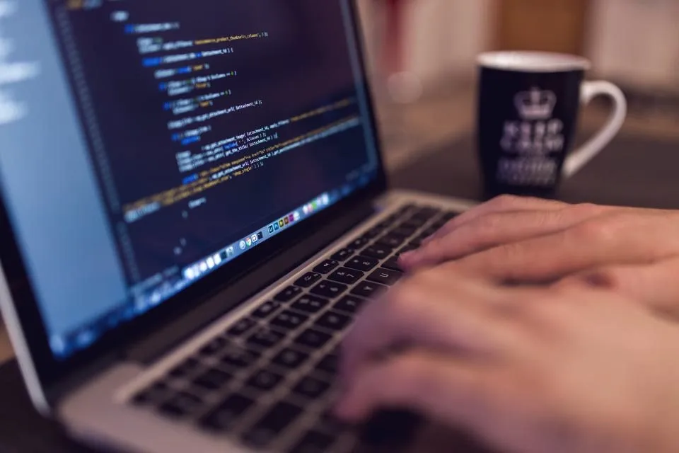 Laptop showing code next to a coffee mug